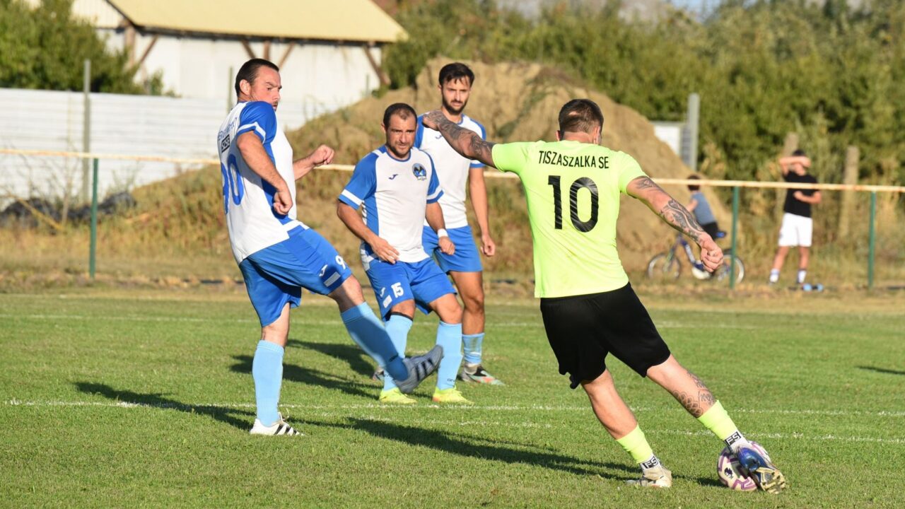 Jucători amatori într-un meci de fotbal pe un teren cu gazon, la apus, cu poarta în prim-plan