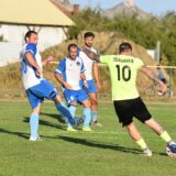 Jucători amatori într-un meci de fotbal pe un teren cu gazon, la apus, cu poarta în prim-plan