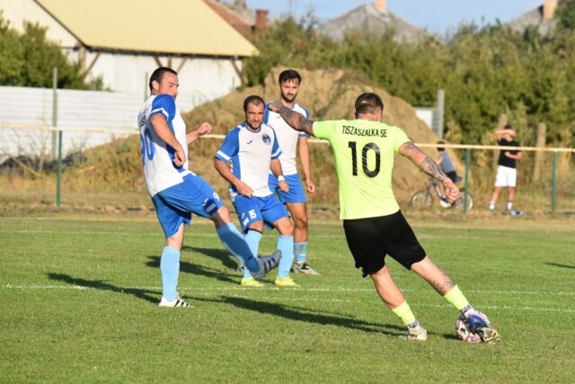 Jucători amatori într-un meci de fotbal pe un teren cu gazon, la apus, cu poarta în prim-plan